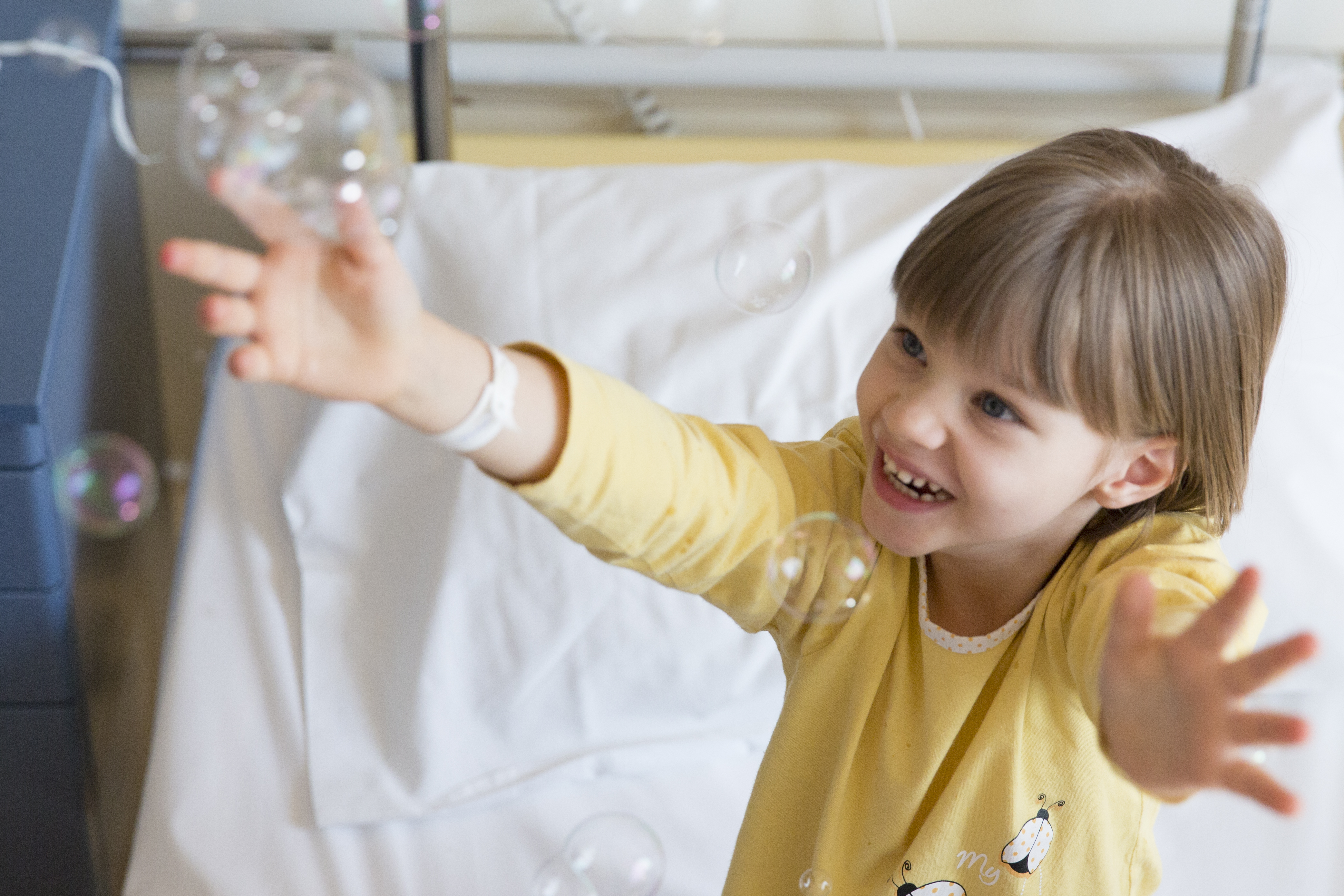 Girl in hospital bed playing with bubbles